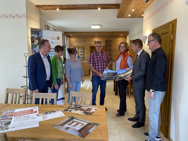 Im ehemaligen Stall und jetzigen Frühstücksraum stehen der Vorsitzende der „Lokalen Aktionsgruppe (LAG) Region an der Romantischen Straße“ Herbert Lindörfer, Regionalmanagerin Andrea Denzinger, Vera und Martin Gögelein, LAG-Geschäftsführerin Pia Grimmeißen-Haider, Landrat Dr. Jürgen Ludwig und Feuchtwangens Bürgermeister Patrick Ruh (v.l.). Darüber liegend wurde eine Wohnung für die Familie der Tochter neu errichtet.  Foto: Landratsamt Ansbach/Josephine Georgi